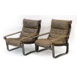 A pair of 1970's brown leather armchairs with slung arms and stained bentwood frames,