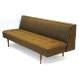 A 1960's brown and button upholstered sofa bed on teak tapering legs,
