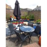 Black circular glass top garden table with 4 black mesh garden chairs and black parasol