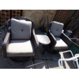 Pair of brown rattan garden armchairs with cushions and matching table