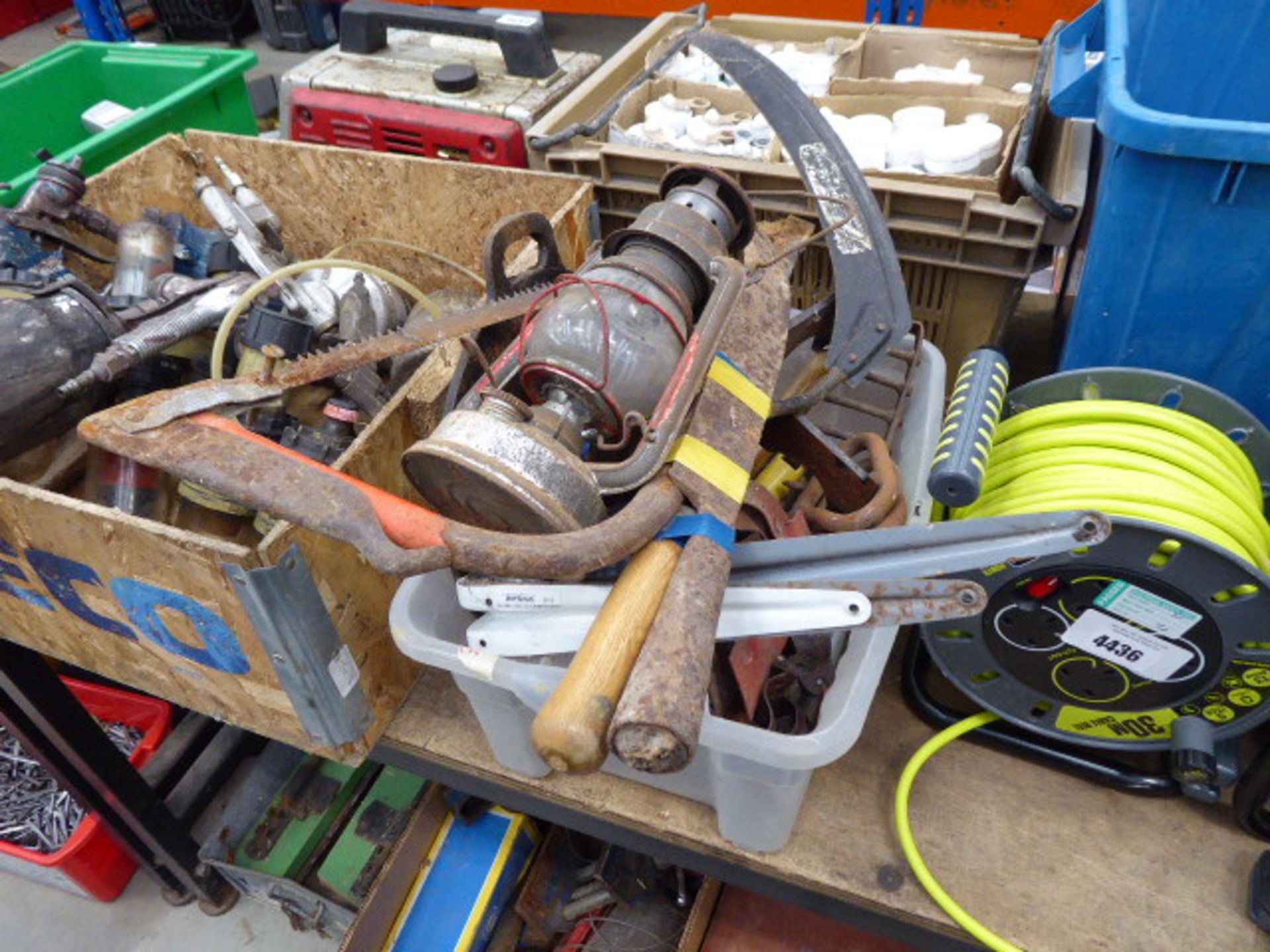 Small plastic crate containing tilley lamps, saw and other tools