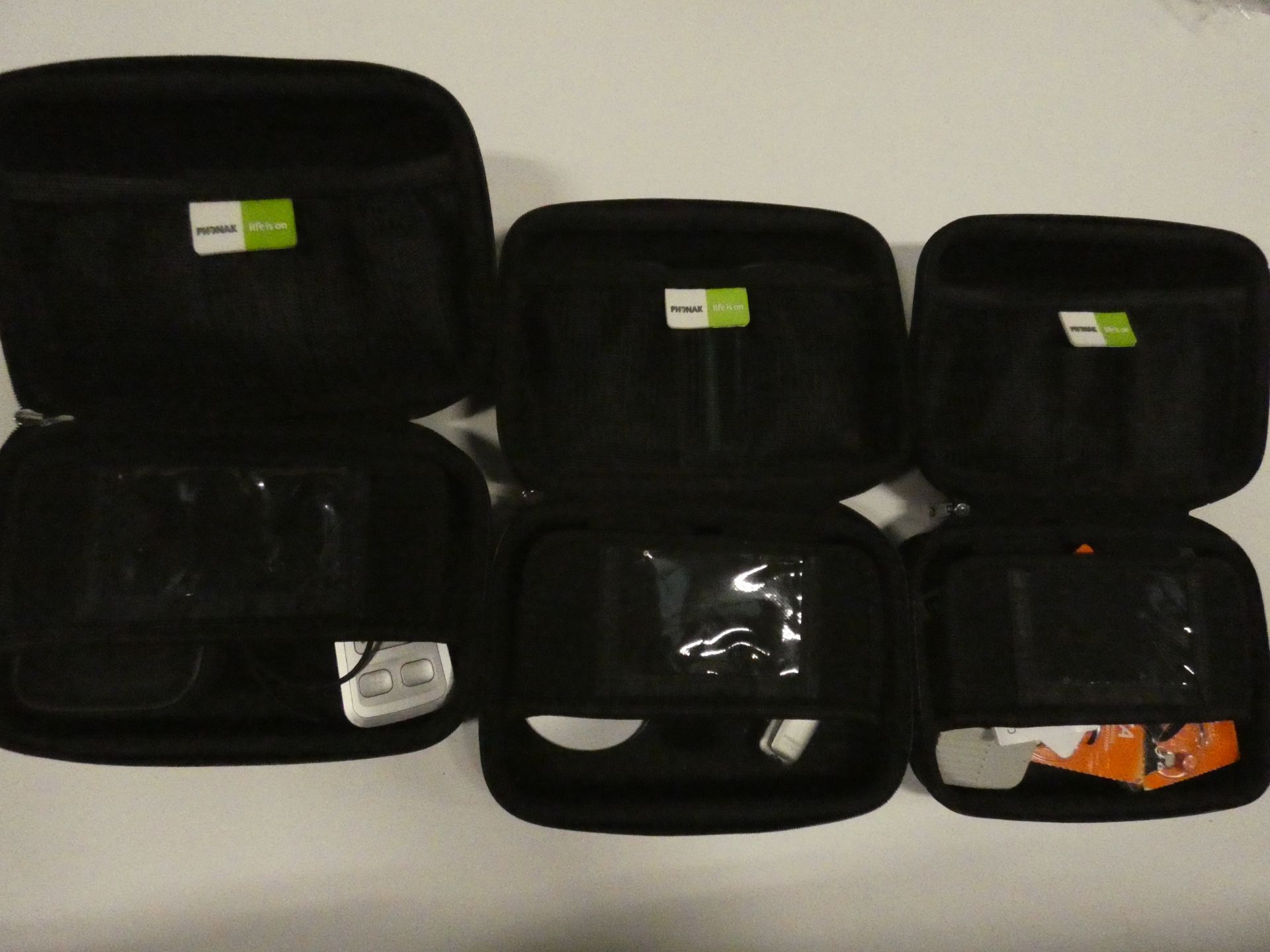 3x Phonax hearing aid cases with various hearing aid accessories