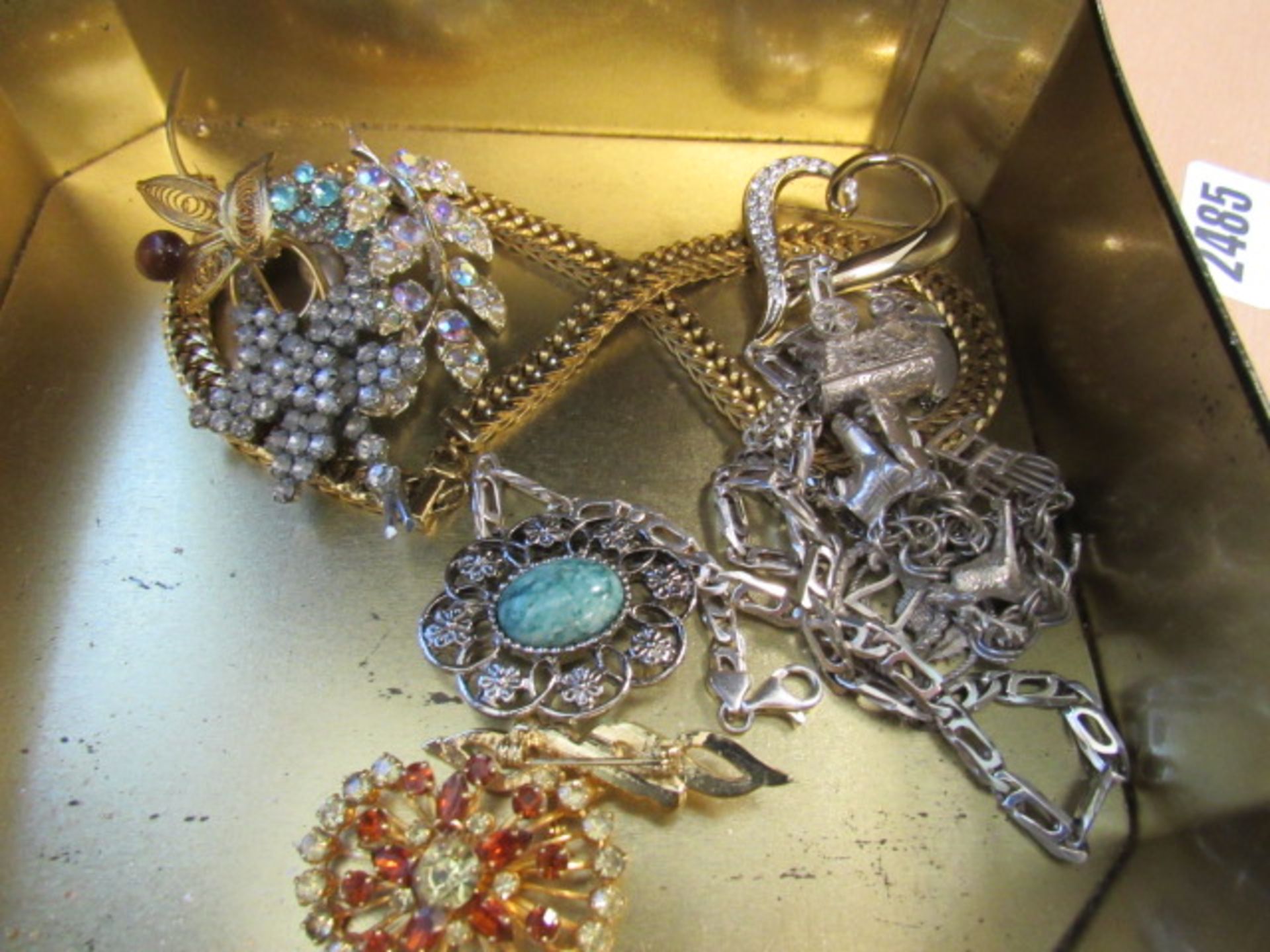 Tin and contents of assorted jewellery inc. charm bracelets, kerb chain necklace, brooches etc