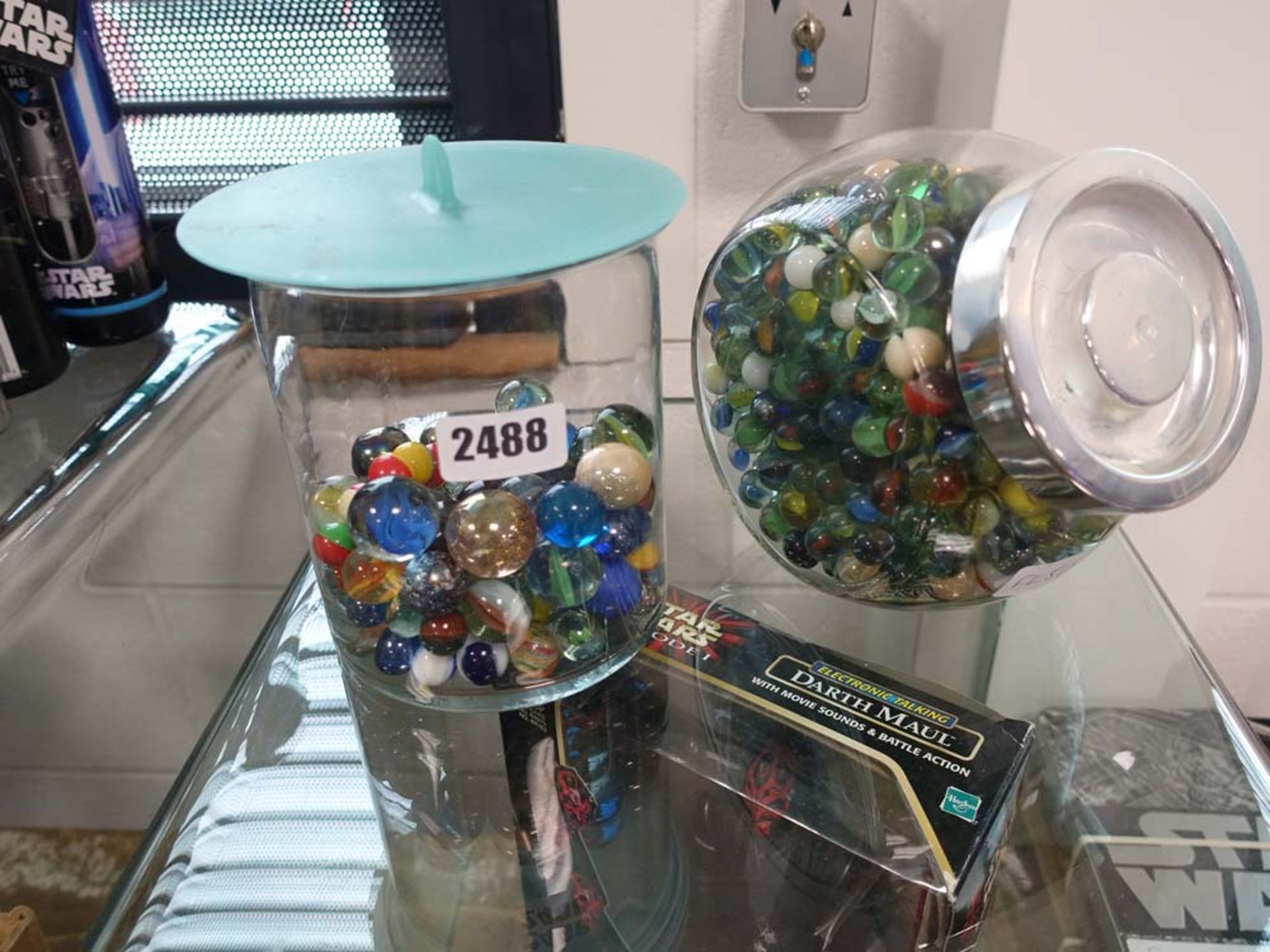 2 glass jars containing a selection of glass marbles