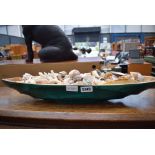 Carved wooden boat shaped bowl with a quantity of seashells