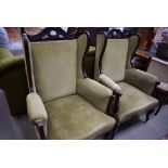 Pair of green upholstered wing back armchairs with carved frames