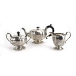 A cased Anglo-Indian metalware three piece tea service of melon shaped form, stamped 'silver',