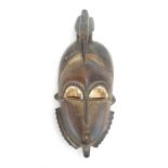 A Senufo, Ivory Coast mask of elongated form surmounted by a bird, h.