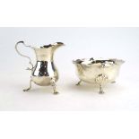 An Edwardian silver cream jug with leaf capped c-scroll handle on three outswept feet, London 1906,