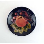 A miniature Moorcroft pin dish decorated with a bird and fruits on a blue ground, d. 11.