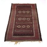 A Persian Baluch Balouch rug, the red ground with tight chevron borders and central patterns,