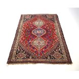 A Persian rug, the red ground with three medallians within matching bands,