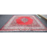A Perisan woolen carpet, the bright red ground with a central floral medallian and matching bands,
