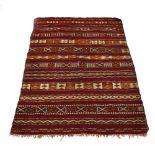 An Uzbek kilim, the red ground with rows of repeated geometric designs,