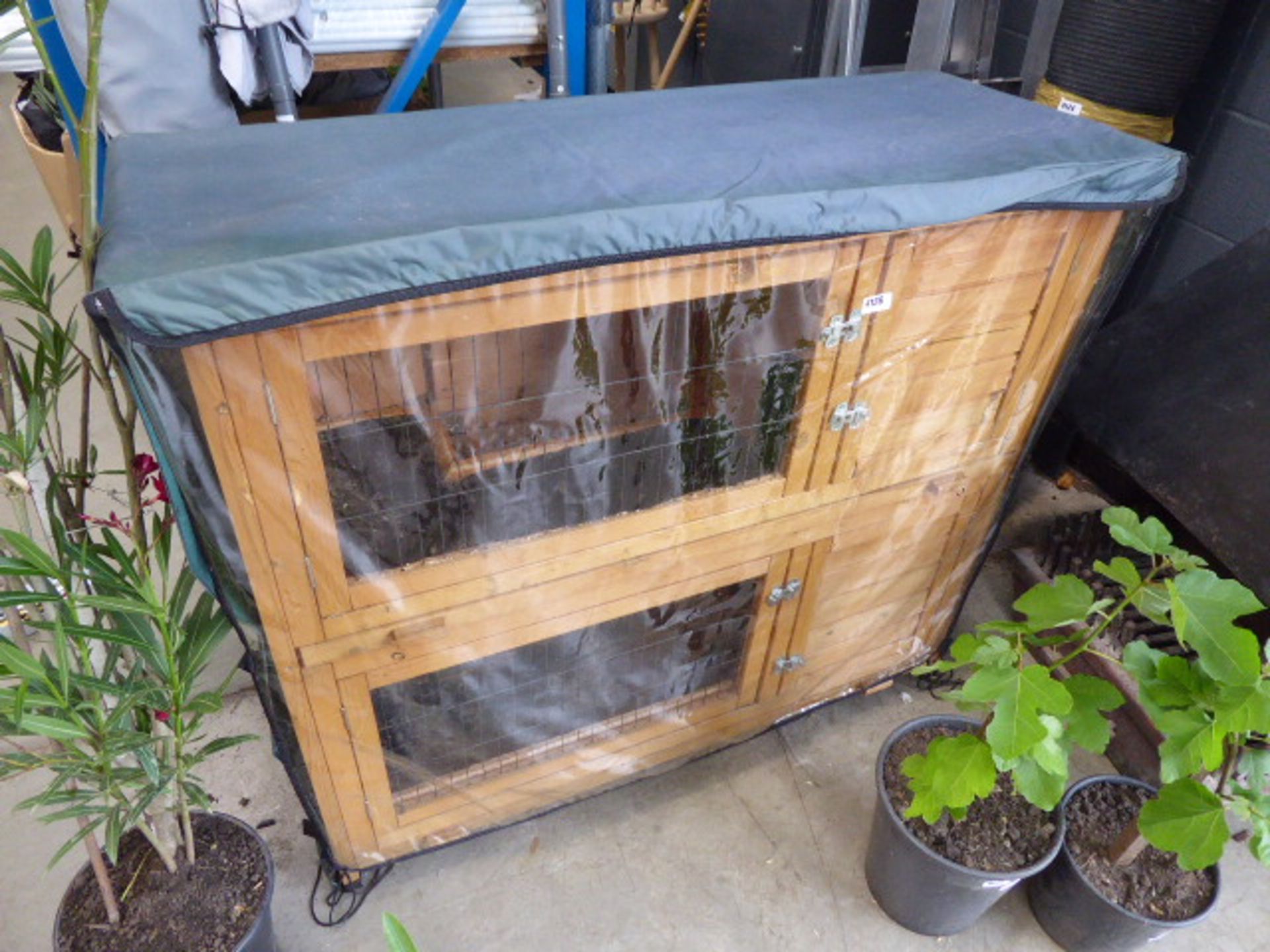 Two storey wooden rabbit hutch with a weather cove