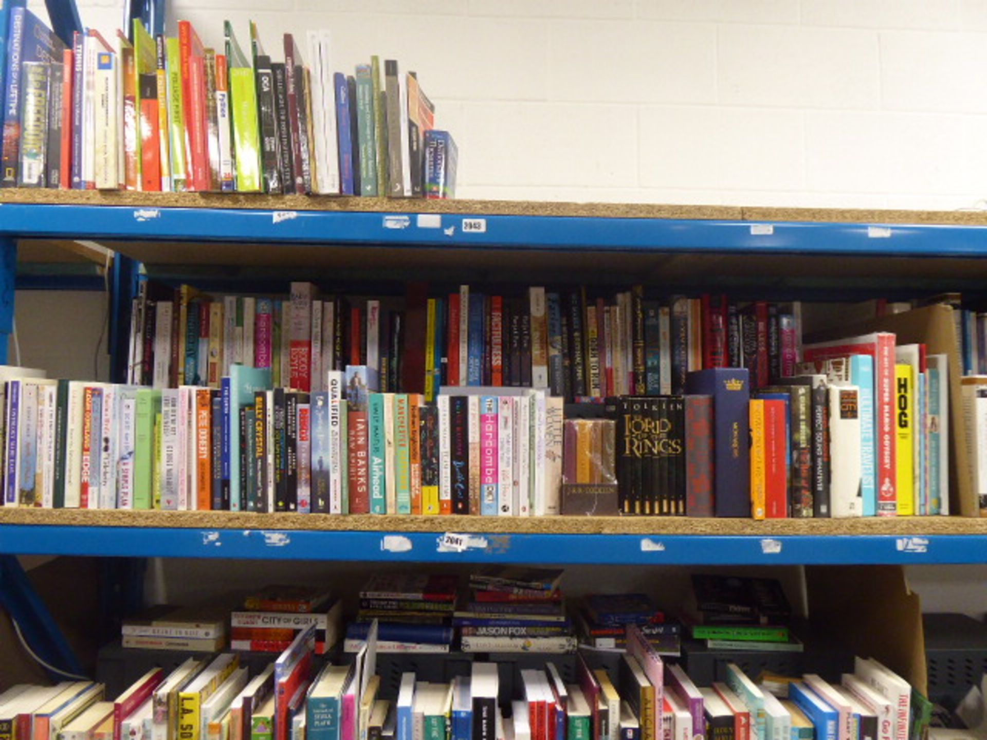 Shelf containing a selection of hard back and paperback novels, reference and other books.