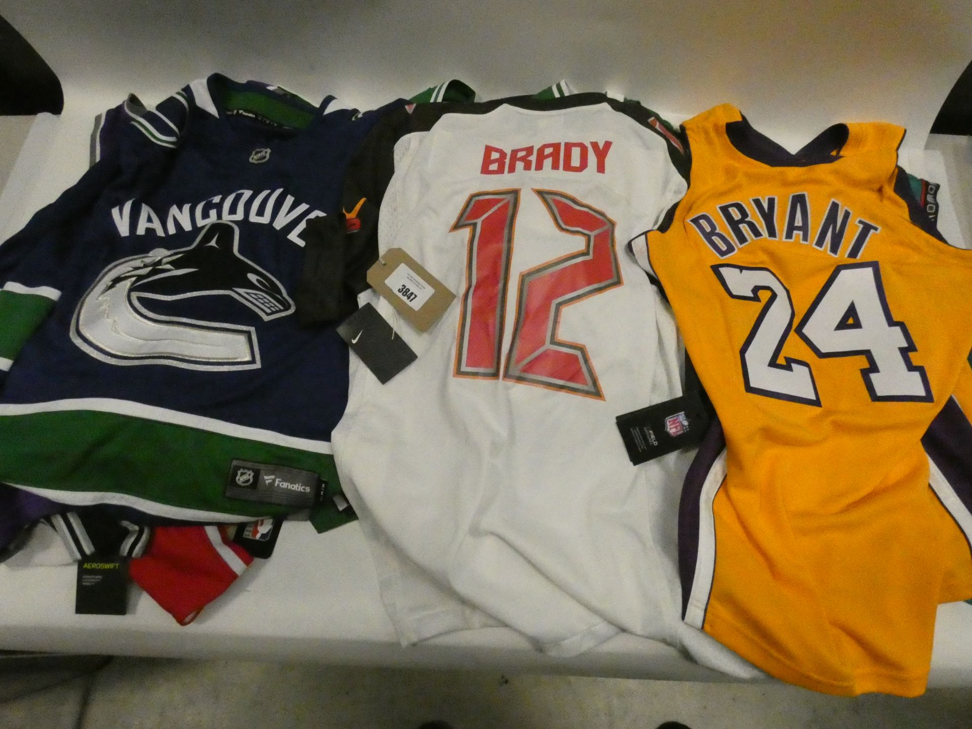 Large bag containing NBA, NHL and NFL jerseys in various sizes (some used)