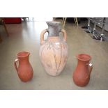 A large terracotta 2 handle pot and 2 terracotta jugs