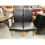 A pair of black leather effect dining chairs