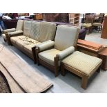 A teak framed three seater sofa, a pair of matching armchairs and footstool