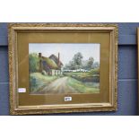 Framed and glazed watercolour of a country cottage with lady hanging out washing, signed J.B