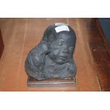 (G) Concrete figurine of a child's head on wooden plinth