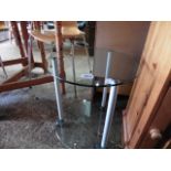 Circular glass top table on castors with shelf below