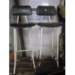 Pair of industrial type metal framed stools with vinyl upholstered seats and backs