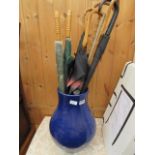 Blue glazed stick stand with a quantity of walking sticks and umbrellas