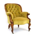 A Victorian walnut armchair with pale green button upholstery on scrolled legs with castors