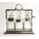 A silver plated three bottle tantalus, w.
