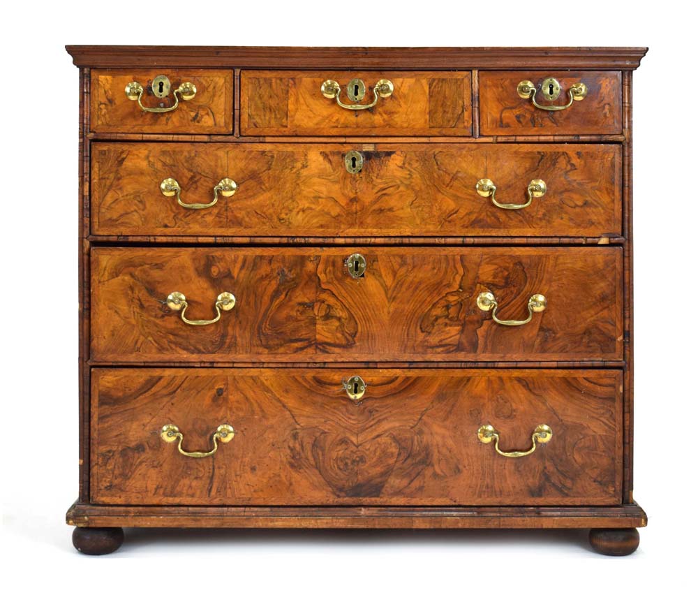 A Georgian walnut and feather crossbanded chest of three short over three long drawers on later bun