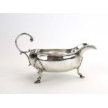A late Victorian silver sauce boat with c-scroll handle and hoof feet, makers marks rubbed,