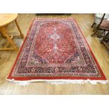 An Iranian carpet, the red ground with a geometric pattern within matching bands,