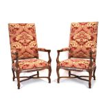 A pair of early-20th century carved mahogany and florally upholstered highback fauteuils,