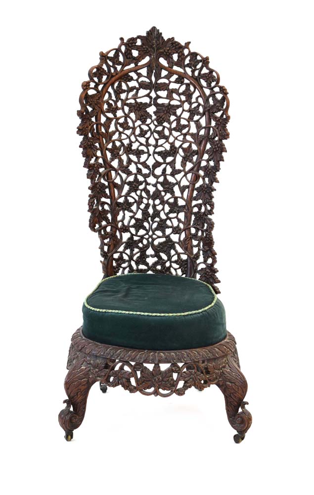 An Anglo-Indian fretwork hall chair intricately carved with fruiting vines,