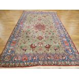 An Iranian carpet, the green ground with floral sprays within blue and red bands,