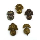 A group of five grenade-type cap badges including Northumberland Fusiliers, Royal Munsters etc.