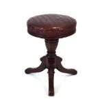 A Victorian mahogany adjustable piano stool with a pressed burgandy seat,