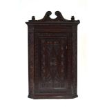 An 18th century corner cabinet with later wheel and geometric carvings below a scrolled pediment, h.