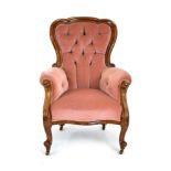 A Victorian mahogany and button upholstered armchair in pale pink on scrolled legs with castors