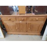 A pine sideboard with three drawers, three doors under