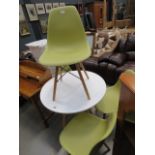 Circular painted beech table with four green molded plastic chairs