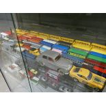 Shelf containing mainly diecast buses and a small collection of diecase vans and cars