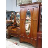 A dark wood dressing table with oval mirrors and a matching single door mirrored wardrobe