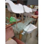 Glass extending dining table on wooden supports with 6 white plastic tub chairs on beech supports
