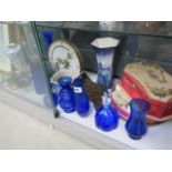 A shelf of assorted china, to include: blue glass, Delfware jug, owl figurines and a clock