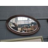 5759 - An oval bevelled mirror in oak frame