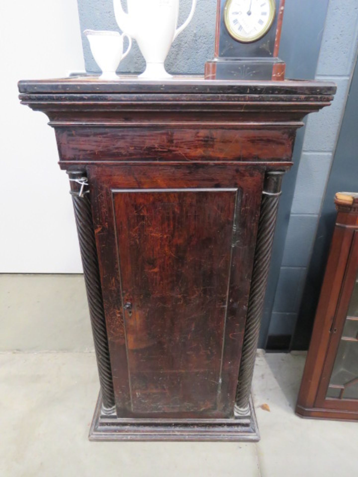 Dark wood single door plinth cupboard with barley twist supports