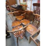 An elm seated stick back armchair, plus four dining chairs